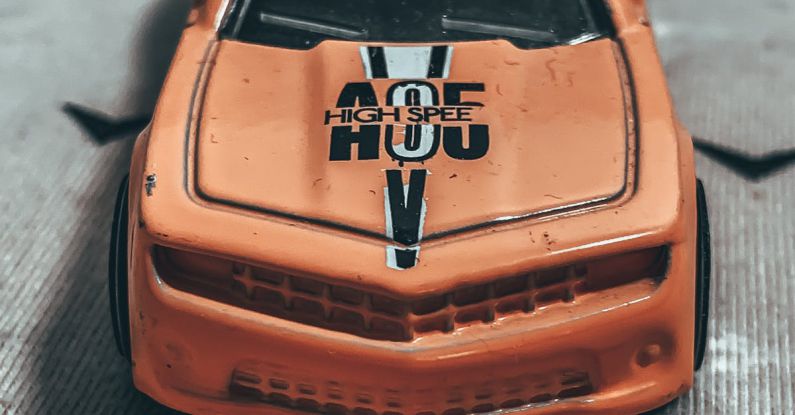 Fuel Line - From above of small miniature of weathered orange toy car placed on rough carpet