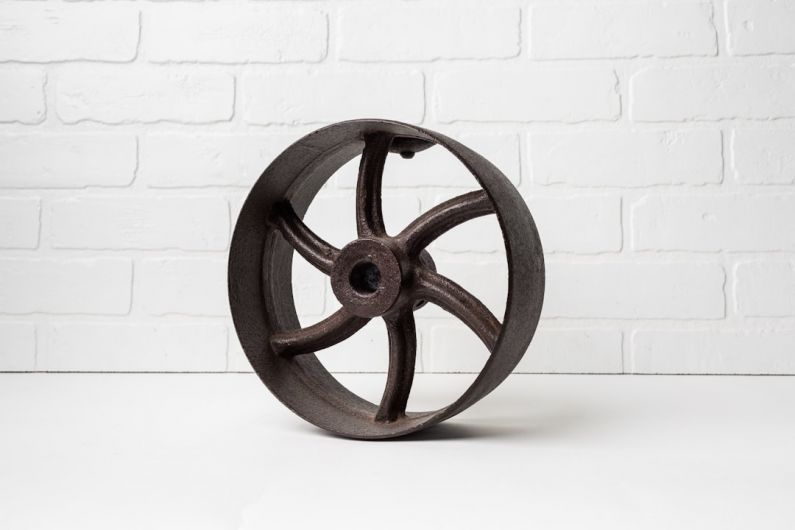 Flywheel - a metal wheel on a white table