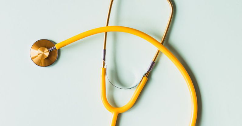 Diagnostic Tool - Top view of yellow medical stethoscope placed on white surface during coronavirus pandemic