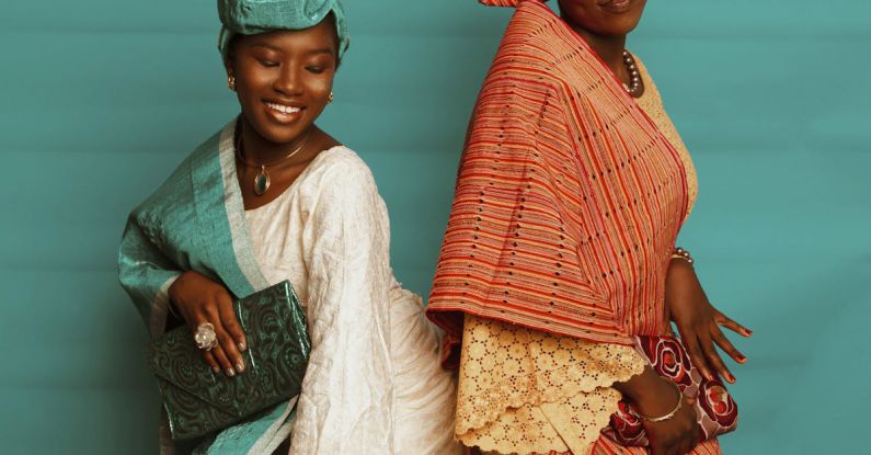 Clutch - Two Elegant Women in Maxi Dresses and Headscarves Posing in a Studio